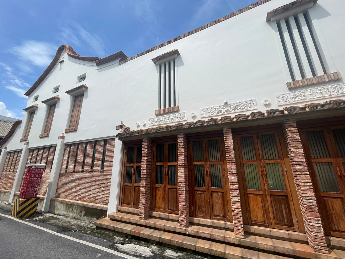 Maison commerçante de style Nanyang restaurée à Songkhla, avec des murs blanc cassé, des détails en briques, des volets en bois et des toits courbés, reflétant l’héritage chinois, malais et thaï. Architecture Nan Yang